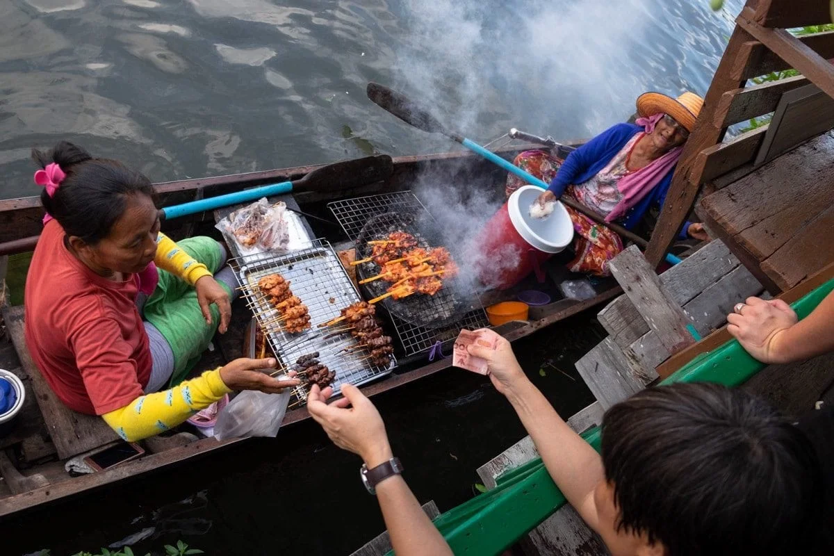 Barbecue chicken sellers on a boat serve people on the banks of Bang Luang Canal.