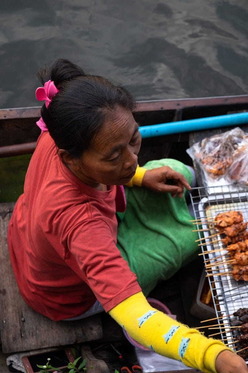 Close up of a barbecue chicken seller on a boat serving people on the banks of Bang Luang Canal.