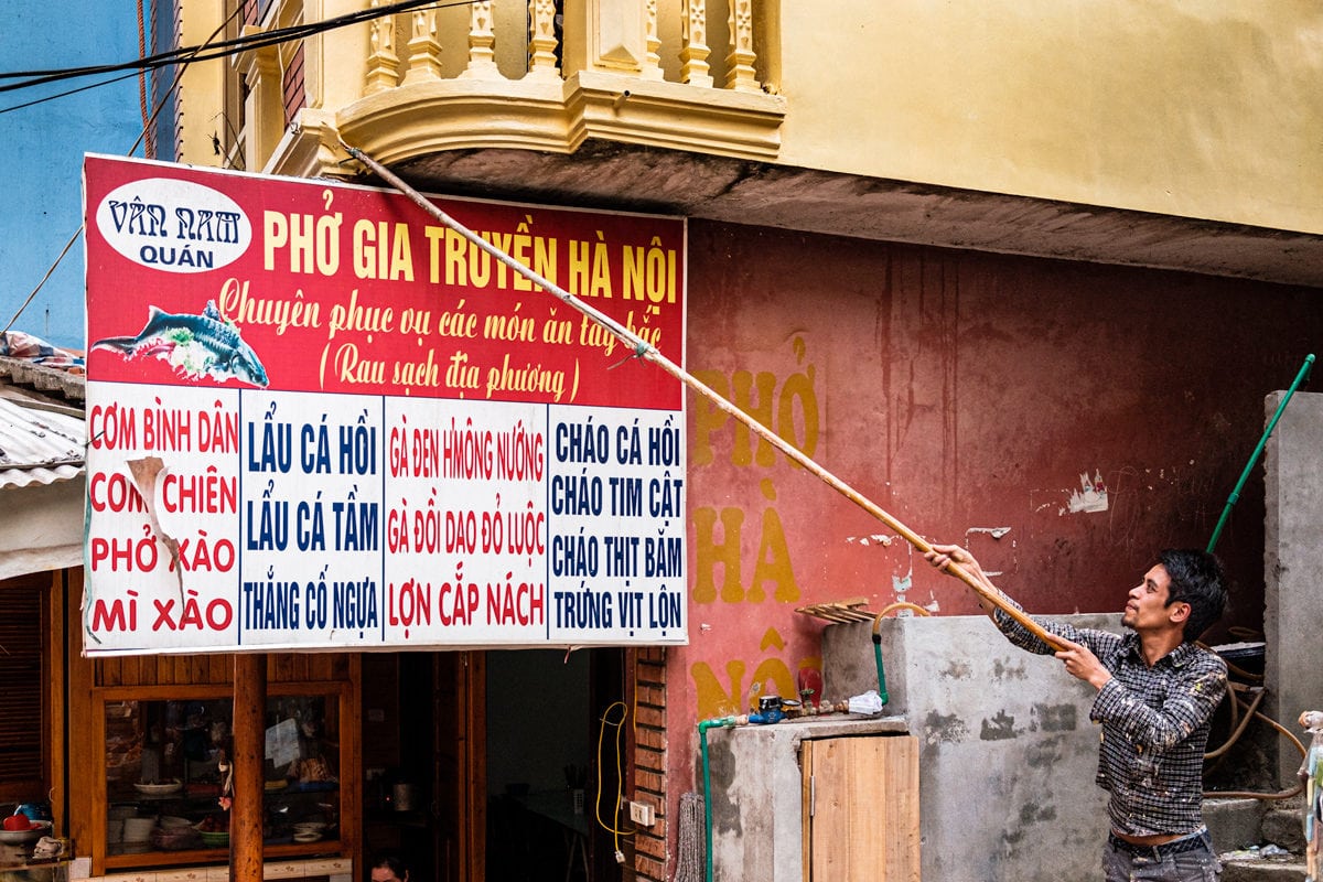 Vietnamese decorator uses a handmade extension pole paint brush to decorate a balcony. Sapa, Vietnam.