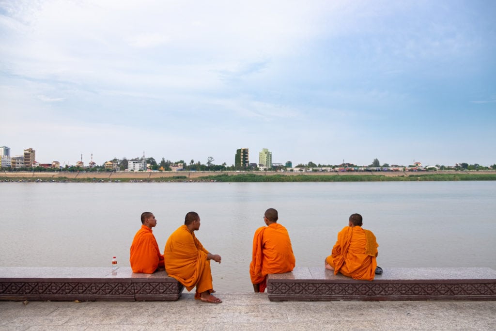Four Buddhist monks by Phnom Penh riverside. Phnom Penh, Cambodia.