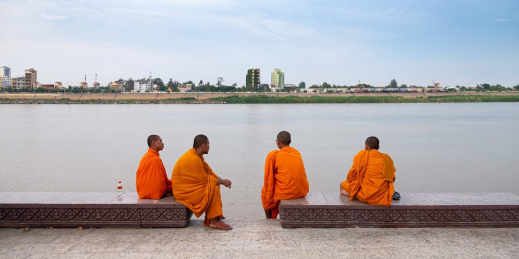 Four Buddhist monks by Phnom Penh riverside. Phnom Penh, Cambodia. Travel photos of Cambodia.