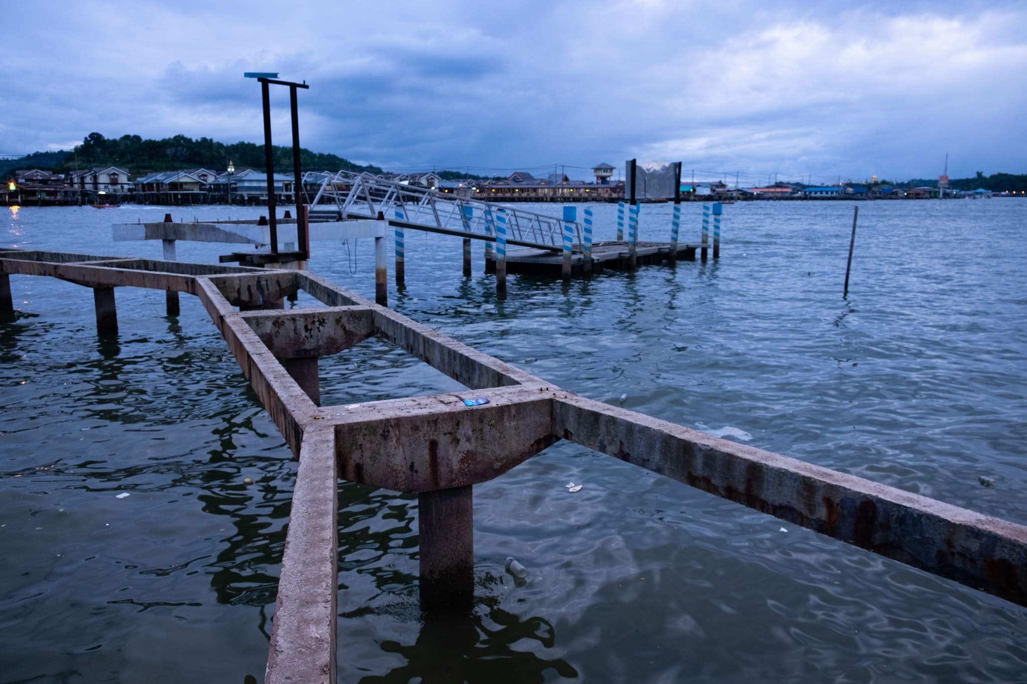 Old pier in a littered waterfront. Bandar Seri Begawan, Brunei. Old and broken pier in a littered waterfront of Bandar Seri Begawan, Brunei.