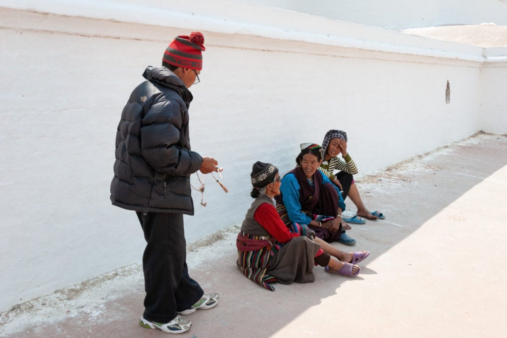 Nepalese hill people take a rest in the shade at Boudhanath Stupa. Kathmandu, Nepal.