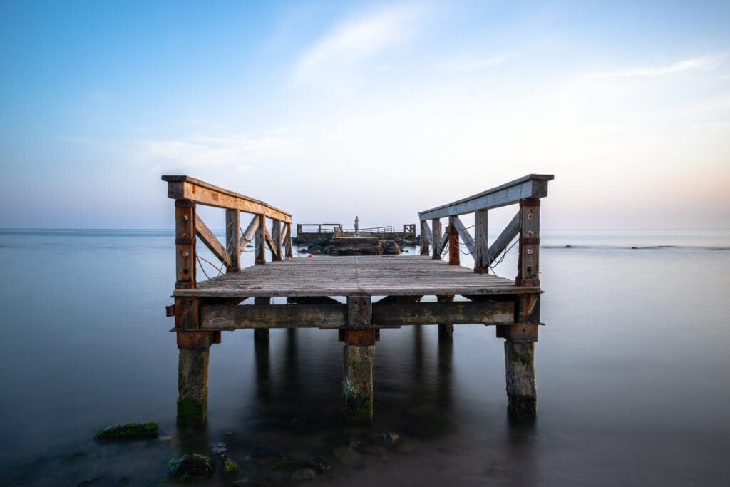 Long exposure of Fishermen's Pier Remains. Lido (Shore) di Ostia. Rome, Italy. Sea water and clouds look smooth and silky.
