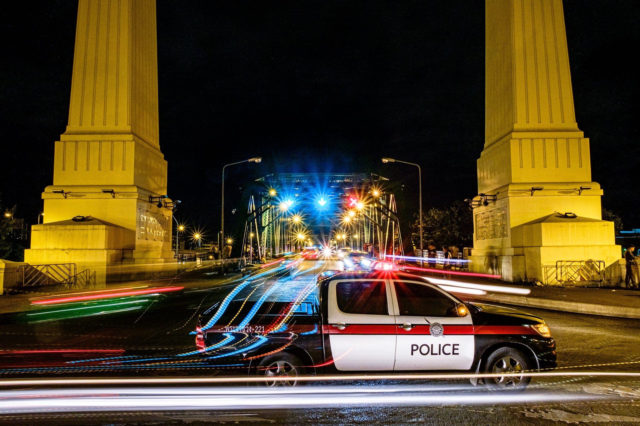 Police car with light trails on the Memorial Bridge (Saphan Phut). Bangkok, Thailand.