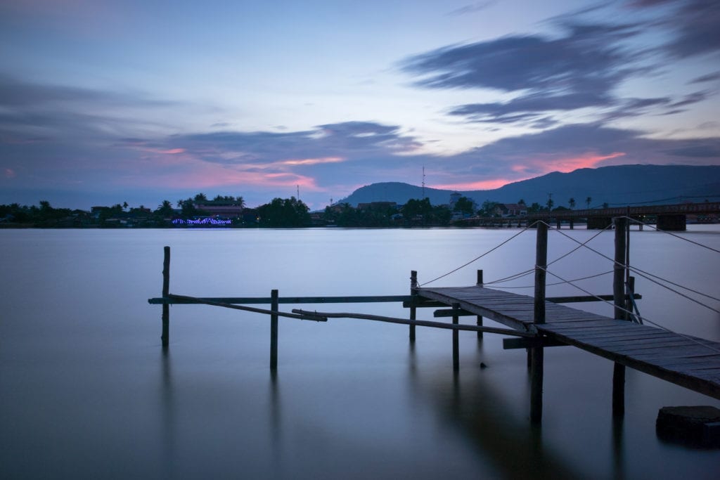 Wooden pier on Kampot River in twilight. Kampot, Cambodia. Water and clouds look smooth and silky because of the long exposure.